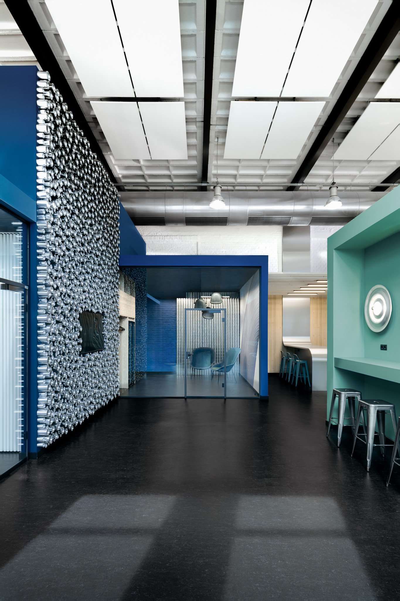 Innenarchitektur eines Bildungscampus in ehemaliger Industriehalle mit blauem Seminar-Cube, Metallinstallationen und offenem Hallenraum