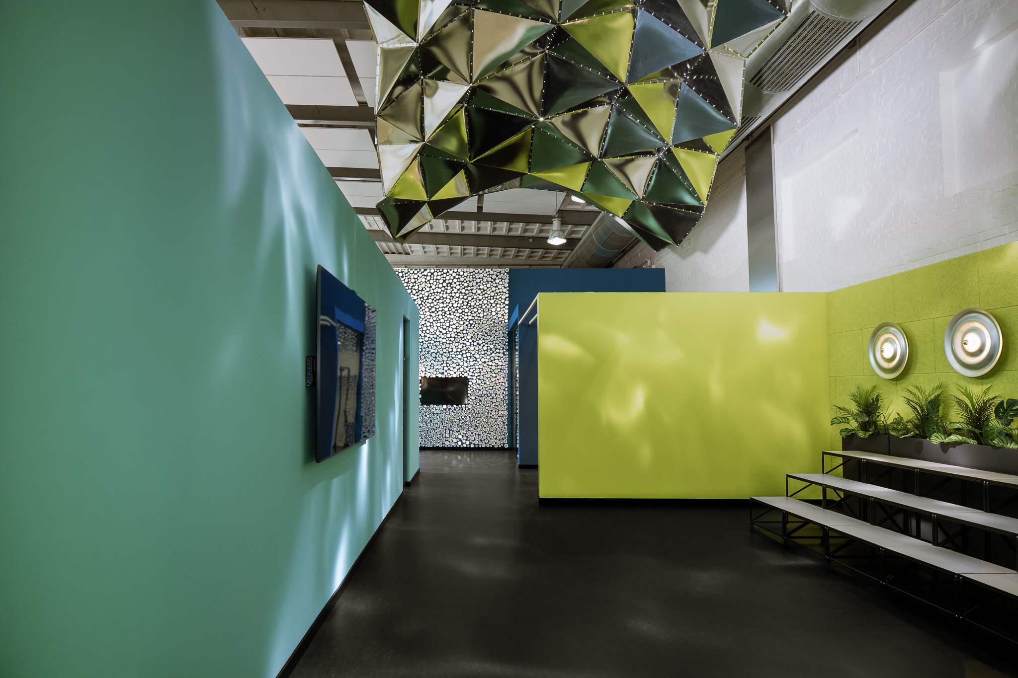 Offene Lernlandschaft mit farbigen Cubes, schwarzer Tribüne und schwebendem Metallkunstwerk in einer umgebauten Industriehalle